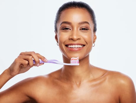 Portrait, dental and a black woman brushing teeth in studio isolated on a white background for oral hygiene. Face, toothbrush and toothpaste with an attractive young female posing on blank space.