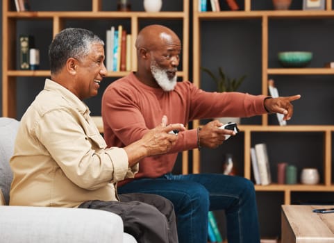 Gaming, pointing and senior black man friends playing a video game together in the living room of a home. Sofa, funny or retirement with a mature male gamer and friend enjoying a house visit to game.
