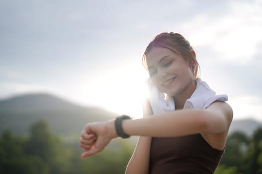 Young woman jogging and looking at her smart wrist watch, copy space, outdoor.