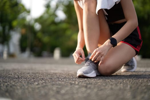 Running shoes. close up female athlete tying laces for jogging on road. Runner ties getting ready for training. Sport lifestyle. copy space.