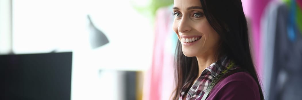 Smiling female fashion designer with scissors in hands in atelier. Tailoring service concept