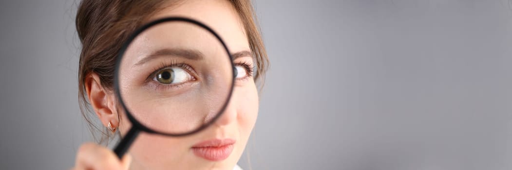 Inquisitive young woman looking through magnifying glass. Search for business ideas and new creative creative information