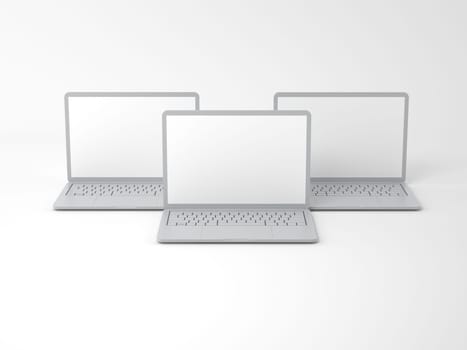 Three open modern gray laptops with blank screens on a light background