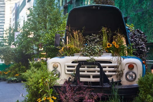 Moscow, Russia - 30.07.2022: An old blue truck filled with a variety of plants and blooms. Flower bed in Moscow, Russia. High quality photo