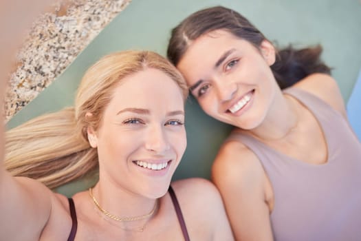 Selfie, yoga and overhead with woman friends lying on the ground while taking a photograph outdoor together. Fitness, social media or pilates with a female yogi and friend resting after a workout.