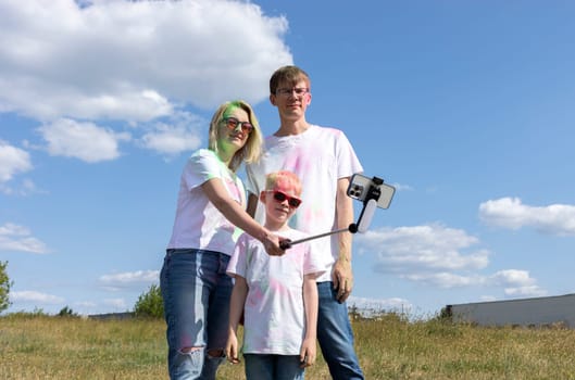 Caucasian Family Takes Photo On Smartphone. Parent, Child With Colorful Dye At Birthday Party Or Celebrating Holi Color Festival. Cheerful Family Spend Time Together. Horizontal Plane.