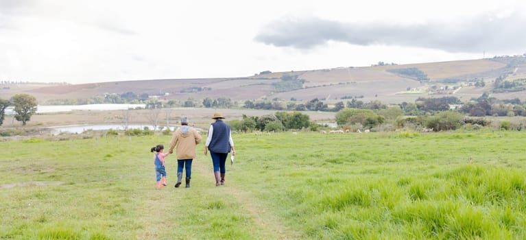 Agriculture, field in countryside with family walking on farm and back view, green and sustainability with agro. Fresh air, farming and farmer with people outdoor, holding hands and environment.