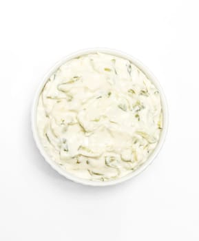 Isolated traditional greek yogurt sauce Tzatziki,dressing in white bowl, made of grated cucumbers, sour cream yogurt,olive oil,garlic,herbs on white background. Close up, flat lay, vertical plane