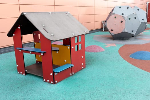 Eco friendly modern colorful children, kids playground, play yard, playset with beautiful soft carpet in campus, without children, Wooden house and dodecahedron with climbing walls. Horizontal.