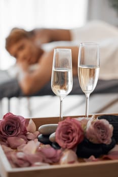 Champagne, massage and couple relax together for a anniversary, love and calm spa experience. Wellness, alcohol with flowers and luxury physical therapy activity of man and woman for romance and rest.