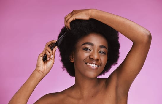 Black woman, hairstyle and afro brush on beauty studio background in grooming routine, texture maintenance or wellness. Happy model, comb and natural hair growth with skincare makeup on isolated pink.