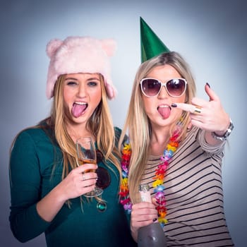 Party, drunk friends and drinking alcohol for celebration while crazy, rude and happy on studio background. Women with wine glass and bottle showing middle finger to celebrate birthday drink together.