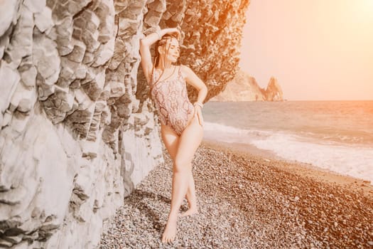 Beach vacation. Hot beautiful woman in sunhat and bikini standing with her arms raised to her head enjoying looking view of beach ocean on hot summer day.