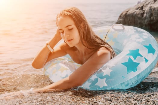 Woman summer sea. Happy woman swimming with inflatable donut on the beach in summer sunny day, surrounded by volcanic mountains. Summer vacation concept