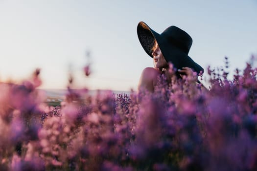 Close up portrait of young beautiful woman in a white dress and a hat is walking in the lavender field and smelling lavender bouquet.