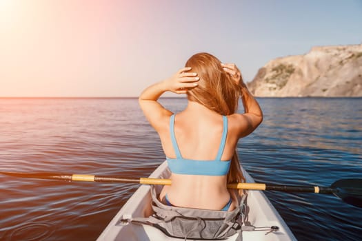 Woman in kayak back view. Happy young woman with long hair floating in transparent kayak on the crystal clear sea. Summer holiday vacation and cheerful female people relaxing having fun on the boat