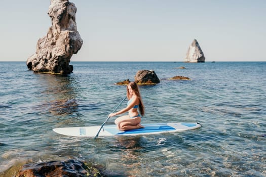 Close up shot of happy young caucasian woman looking at camera and smiling. Cute woman portrait in bikini posing on a volcanic rock high above the sea