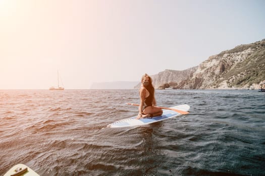 Close up shot of beautiful young caucasian woman with black hair and freckles looking at camera and smiling. Cute woman portrait in a pink bikini posing on a volcanic rock high above the sea