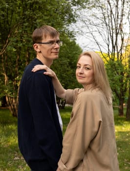 Couple In Park. White Woman Holding Hand On Man's Shoulder. Relationship, Togetherness. Enjoying Time Together. Feelings. Vertical Plane Summer Time.