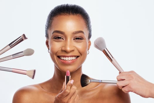 Makeup, beauty brush and lipstick on face of woman portrait in studio for dermatology cosmetics. Happy aesthetic model person with facial tools for healthy skin glow isolated on a white background.
