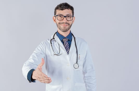 Smiling doctor shaking hands in welcome sign isolated. Friendly male doctor extending hand to camera isolated