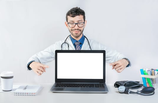 Handsome doctor pointing at an advertisement on the laptop screen. Smiling doctor pointing at an advertisement on the laptop screen