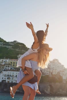 Vacation piggyback, free and women in summer for freedom, city adventure and walking in Spain. Smile, travel and young friends being carefree together on a holiday in a small town by the ocean.