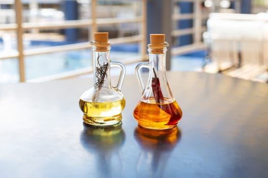 On the table are two glass bottles filled with spicy and rosemary olive oil. Close-up. Butter for pizza, rest in an Italian restaurant