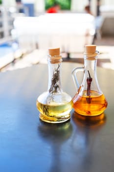 On the table are two glass bottles filled with spicy and rosemary olive oil. Butter for pizza, rest in an Italian restaurant. Close-up