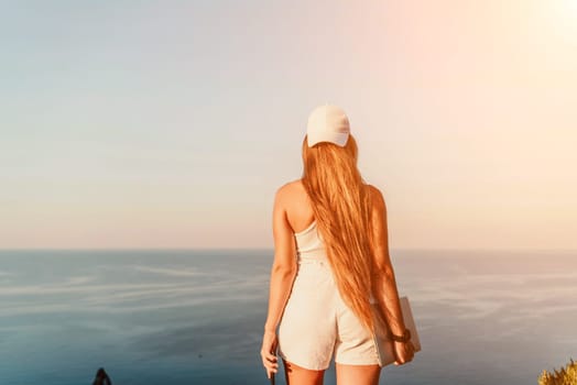 A female tourist stands by the sea wearing a white cap and T-shirt, looking happy and relaxed