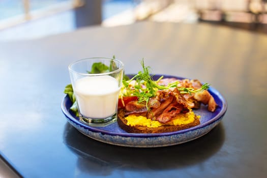Very bright and healthy breakfast on a plate - bacon, egg, salad, tomato, cheese, a glass of yogurt