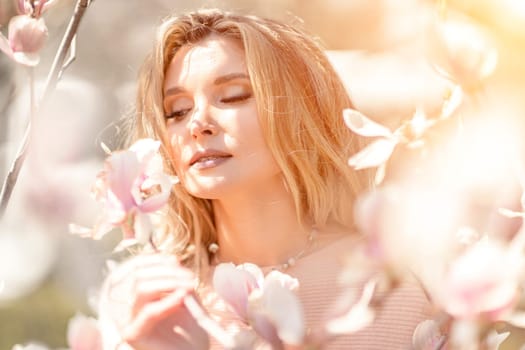 Magnolia woman portrait. Happy middle aged woman enjoying the smell in a blooming spring garden. Beautiful magnolia bushes, large flowers