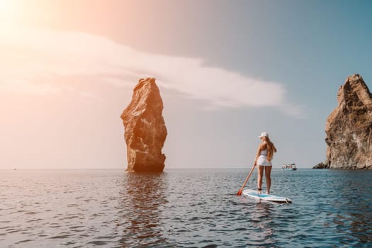 Close up shot of beautiful young caucasian woman with black hair and freckles looking at camera and smiling. Cute woman portrait in a pink bikini posing on a volcanic rock high above the sea