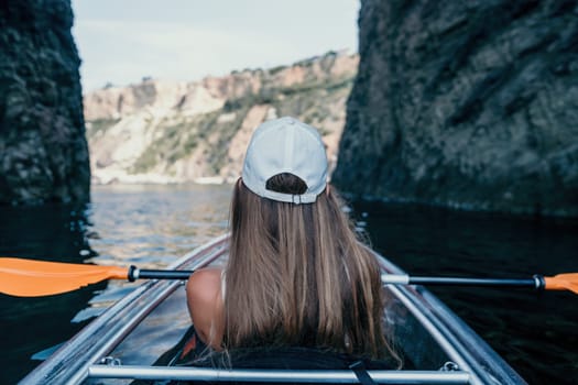 Woman in kayak back view. Happy young woman with long hair floating in transparent kayak on the crystal clear sea. Summer holiday vacation and cheerful female people having fun on the boat.