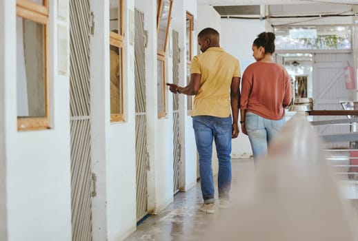 Animal shelter, adoption and charity with a black couple together in a rescue center for community aid. Help volunteer and ngo with a man and woman walking through a kennel for pet adoption.