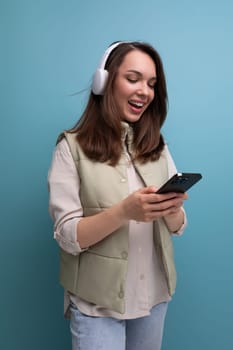 positive 30s lady communicates on the internet using headphones and mobile phone.