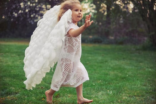 Cute baby dressed as an angel in the evening forest in Denmark.