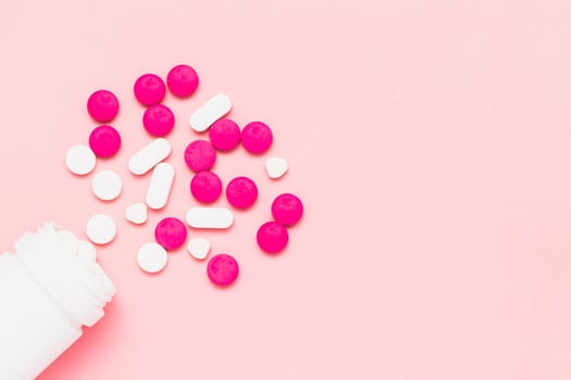 Top view of piles of pills were released from the bottle on pink background for medical and healthcare concept