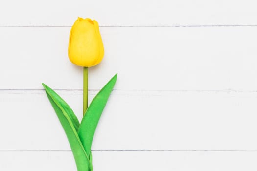 Top view of an artificial yellow tulip on white table background for nature decoration and springtime concept