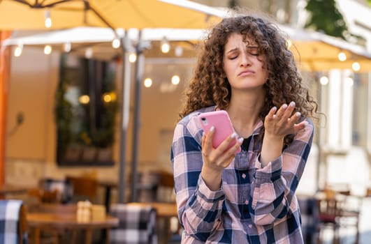 Pretty young woman use smartphone typing browsing, loses becoming surprised sudden lottery results, bad news, fortune loss, fail. Girl walking in urban sunshine city street outdoors. Town lifestyles