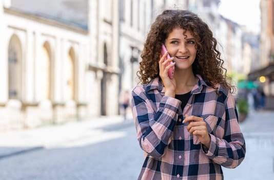 Happy young woman tourist having remote conversation communicate speaking by smartphone. Pretty girl talking on phone unexpected good news gossip walking in urban city street. Town lifestyles outdoors
