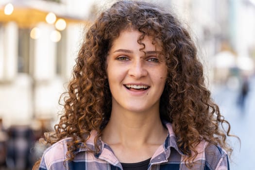 Portrait of happy pretty young woman smiling friendly, glad expression looking at camera dreaming, resting, relaxation feel satisfied good news outdoors. Girl in urban city sunshine street background