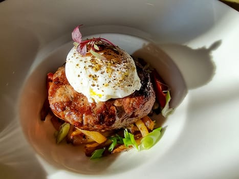 chopped beef cutlet on a pillow of potatoes with lettuce, poached egg and spicy gravy