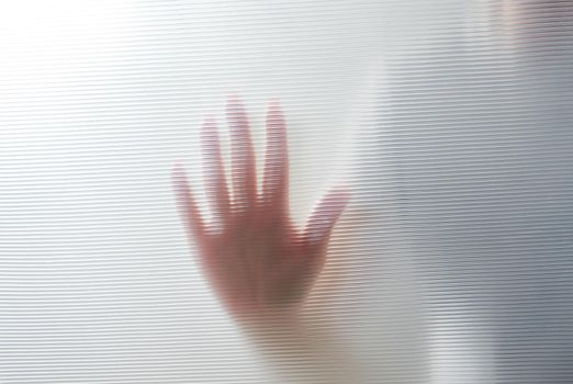 Diffused silhouette of female hands through frosted glass