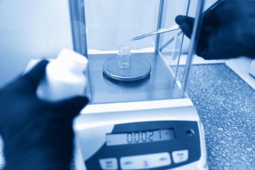 Scientist weighing chemicals by digital scales in grams in the chemical laboratory