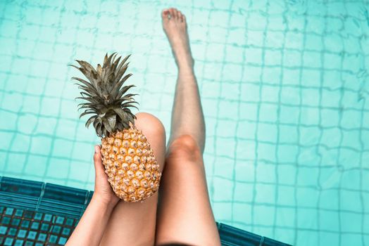 Sexy Woman is Relaxing in Swimming Pool While Holding Pineapple, Close-Up of Beautiful Woman Hold Pineapple and Relax Sunbathe in Poolside on Summer Holiday at Resort Hotel. Summer Vacation Lifestyles