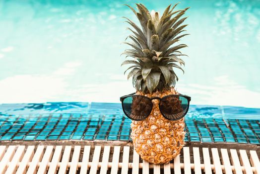 Summer Vacation and Swimming Pool Relaxation Lifestyles Concept, Pineapple With Sunglasses in Poolside at The Beach Vacations. Tropical Leisure Activities Relaxing and Holiday Resort