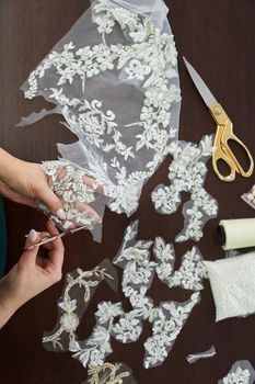 Dressmaker cutting lace fabric for wedding dress decoration