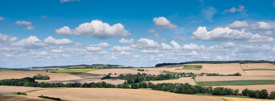 fields, villages and rolling hills in french countryside south of reims under blue sky in summer