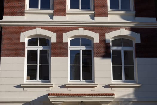 Red brick wall divided by a white cornice and longitudinal windows. A fragment of the fa ade of the historic Daylight Building.